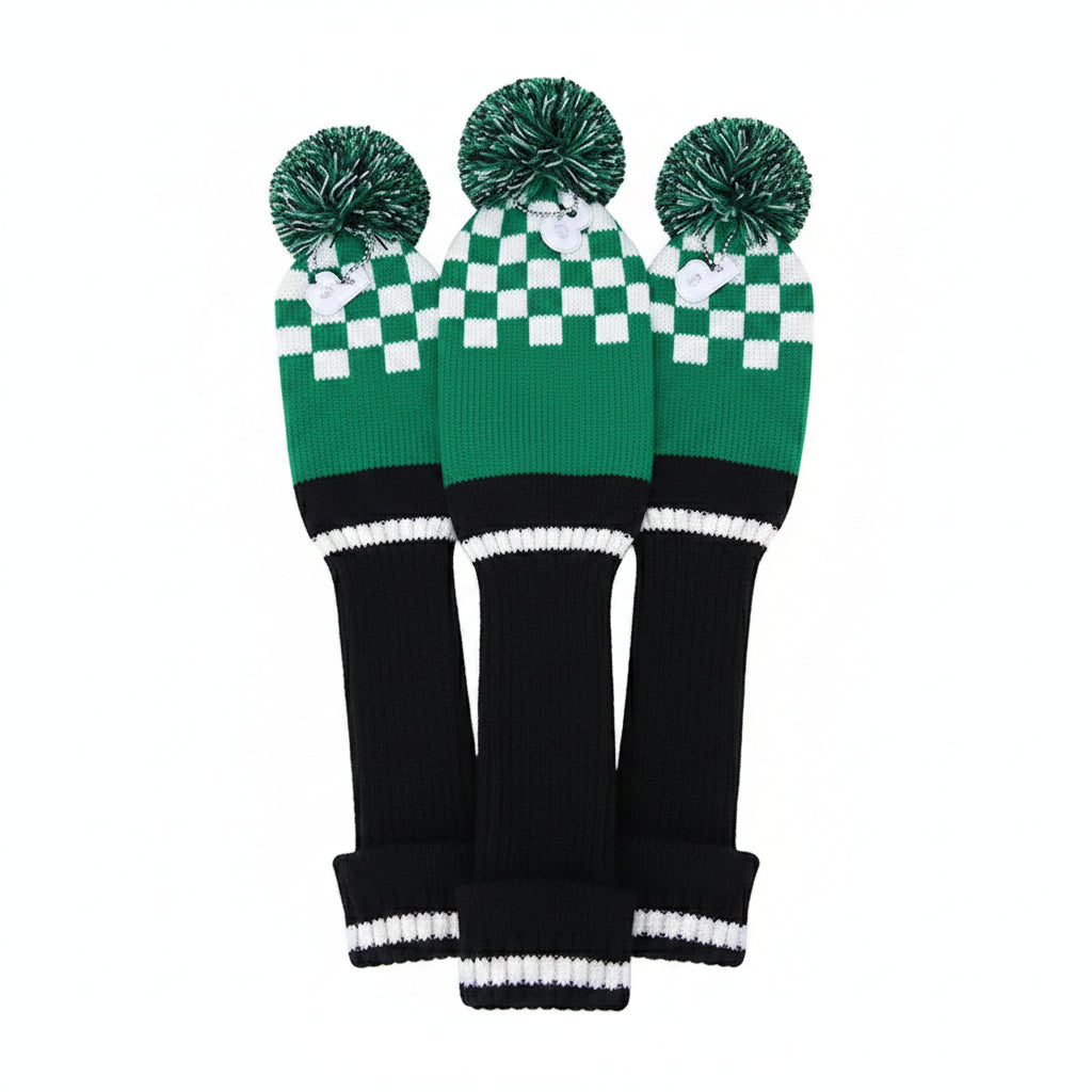 Three green and black checkered golf club covers with pom-poms on a white background