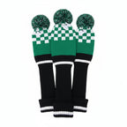 Three green and black checkered golf club covers with pom-poms on a white background