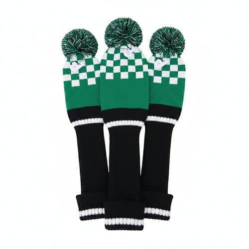 Three green and black checkered golf club covers with pom-poms on a white background